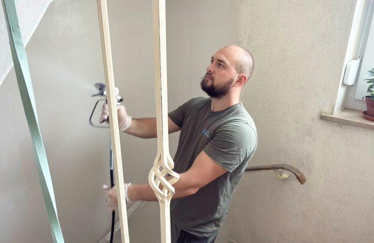 Hausmeister Vlad beim Lackieren eines Treppenhauses mit Sprühpistole in Traunreut